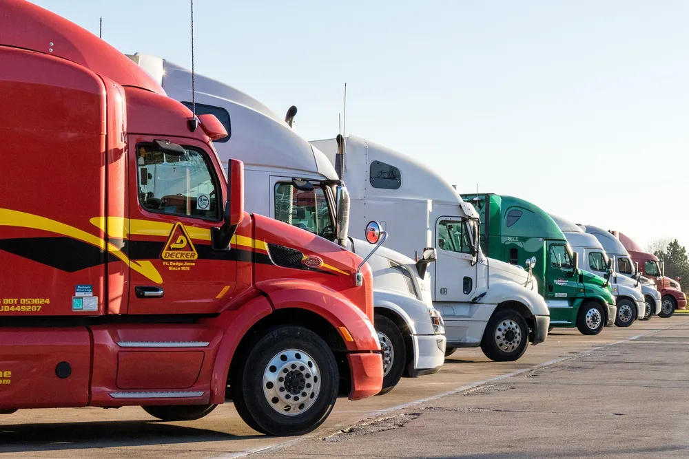 Row of long-haul semi trucks parked at a depot